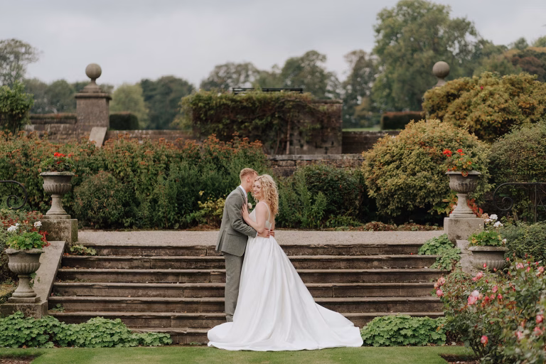 Groom kisses bride on the steps at Tissington Hall
